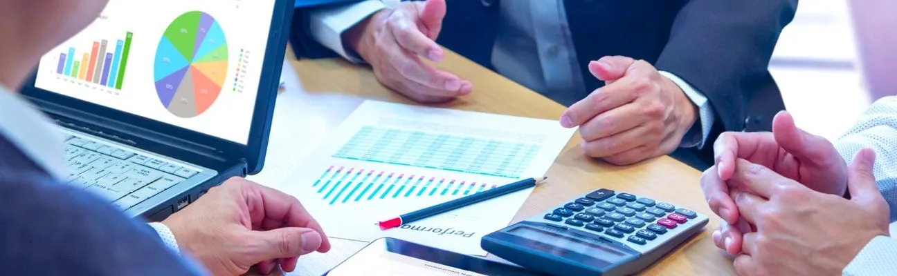 Persone che analizzano grafici finanziari a una scrivania con una calcolatrice