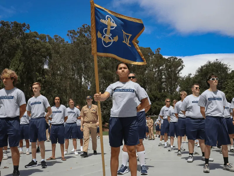 Cadetti in uniforme che sfilano con una bandiera