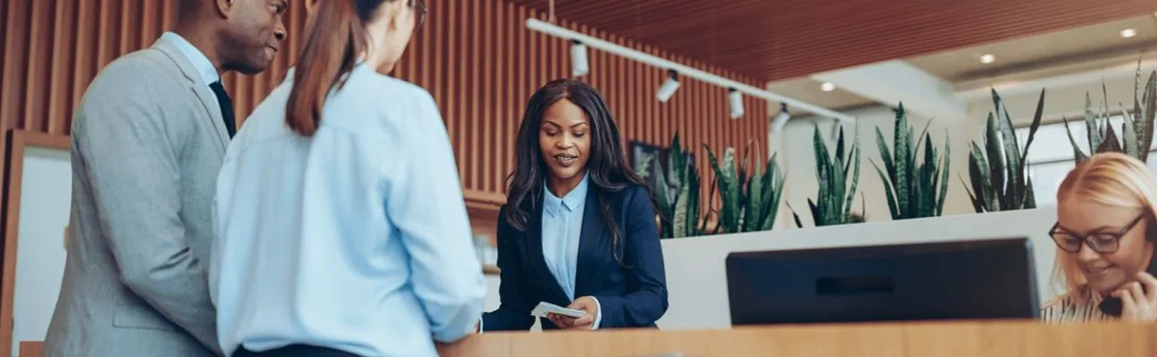 Addetta alla reception di un hotel che aiuta gli ospiti al banco
