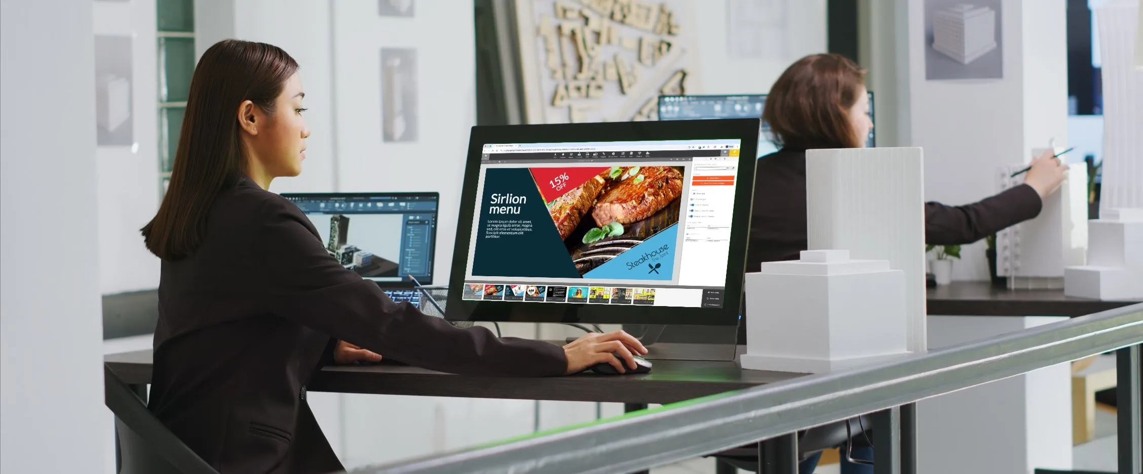Donna che progetta la diapositiva di un menu di steakhouse nell’editor di Play, su un monitor